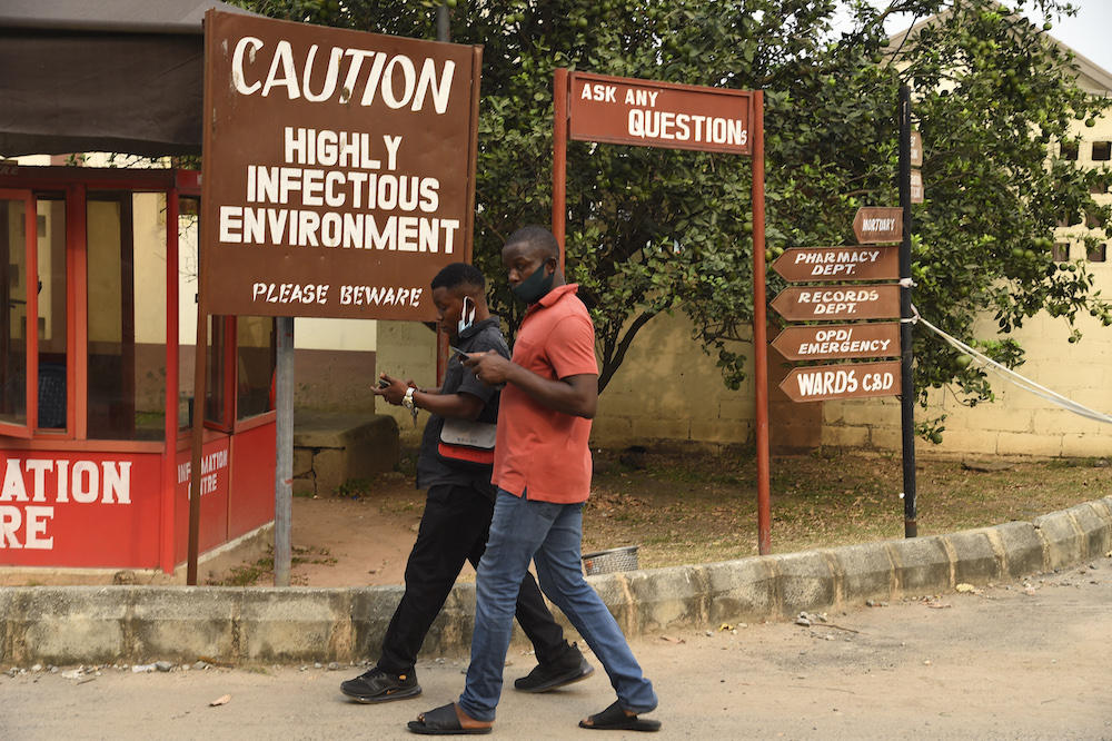 People walk past a signpost to warn visitors of the infectious environment in Yaba, Lagos on Jan. 22, 2021. In 2021, a cholera epidemic killed more than 2,300 people, especially children under the age of 14. (AFP)