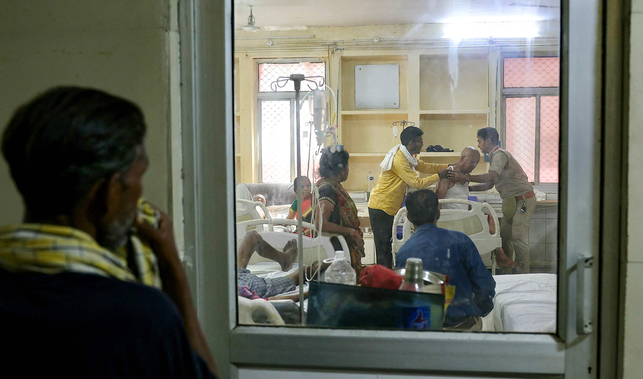 People watch as a patient suffering from heat stroke is helped to get up inside an emergency room in a government hospital during a severe heatwave in Varanasi on May 30, 2024. (AFP)