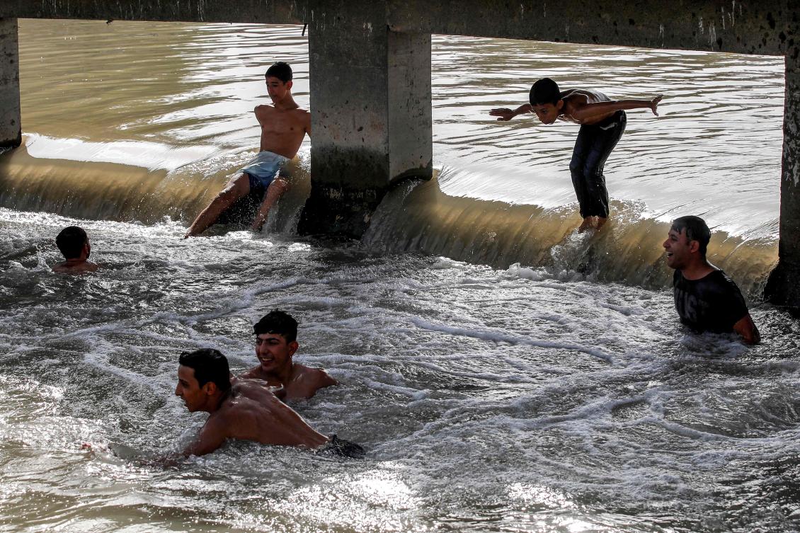 A boy jumps into the water of a canal of the Tigris river in Baghdad amid a soaring heatwave on June 18, 2024 on the third day of the Muslim holiday of Eid Al-Adha. (AFP)