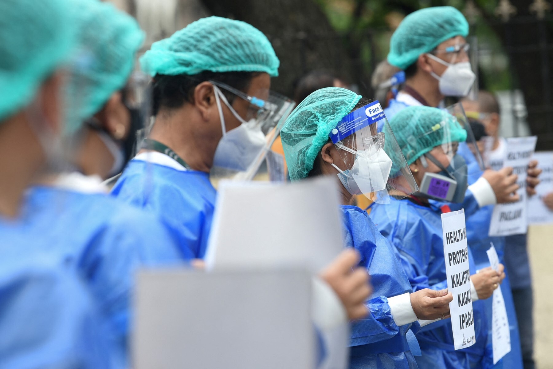 Health workers from the government-run Philippine General Hospital hold placards as they ask the government to release their risk allowances amid rising Covid-19 coronavirus infections, in Manila on Aug. 26, 2021. (AFP/File)
