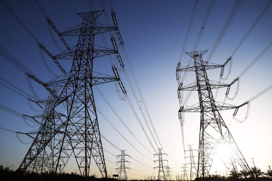 The sun sets behind overhead power lines as the Kuwaiti Ministry of Electricity requested citizens to ration their electricity usage at peak times due to outages caused by the increased pressure on power stations amid soaring temperatures and heightened energy demand.(AFP)