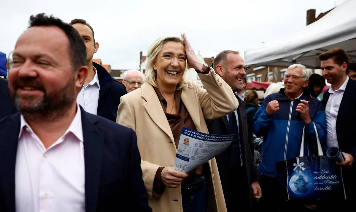 French far-right leader Marine Le Pen and French far-right National Rally party candidate in the upcoming parliamentary elections, distributes leaflets as she campaigns with Henin-Beaumont mayor Steeve Briois and local RN politician Bruno Bilde at a market in Henin-Beaumont, northern France on June 14, 2024. (Reuters)