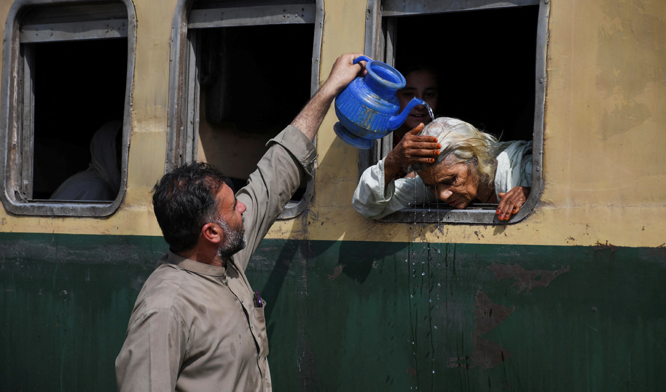 A woman from a train window receives water on her head to cool off during a hot and humid day at the Hyderabad Railway Station in Hyderabad, Pakistan on May 22, 2024. (REUTERS)