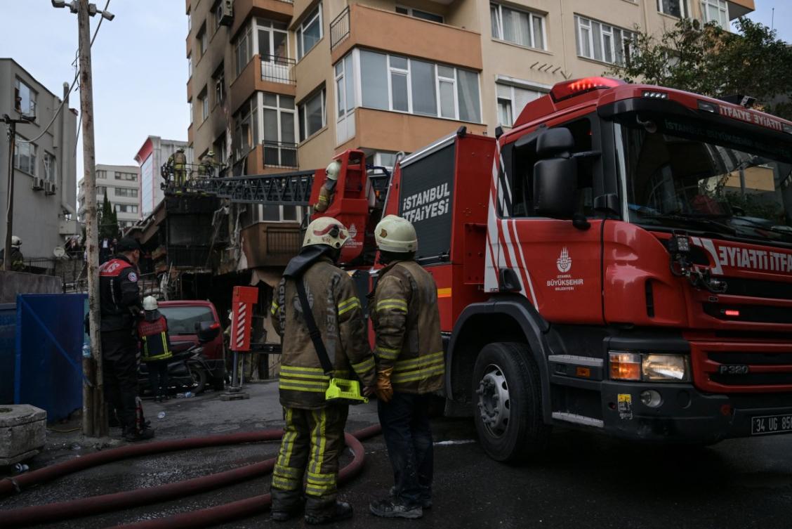 Firefighter on the ground look on as fellow rescue workers climb a ladder to intervene at the site of a burnt residential building after a fire broke out, in Istanbul on April 2, 2024. (AFP)