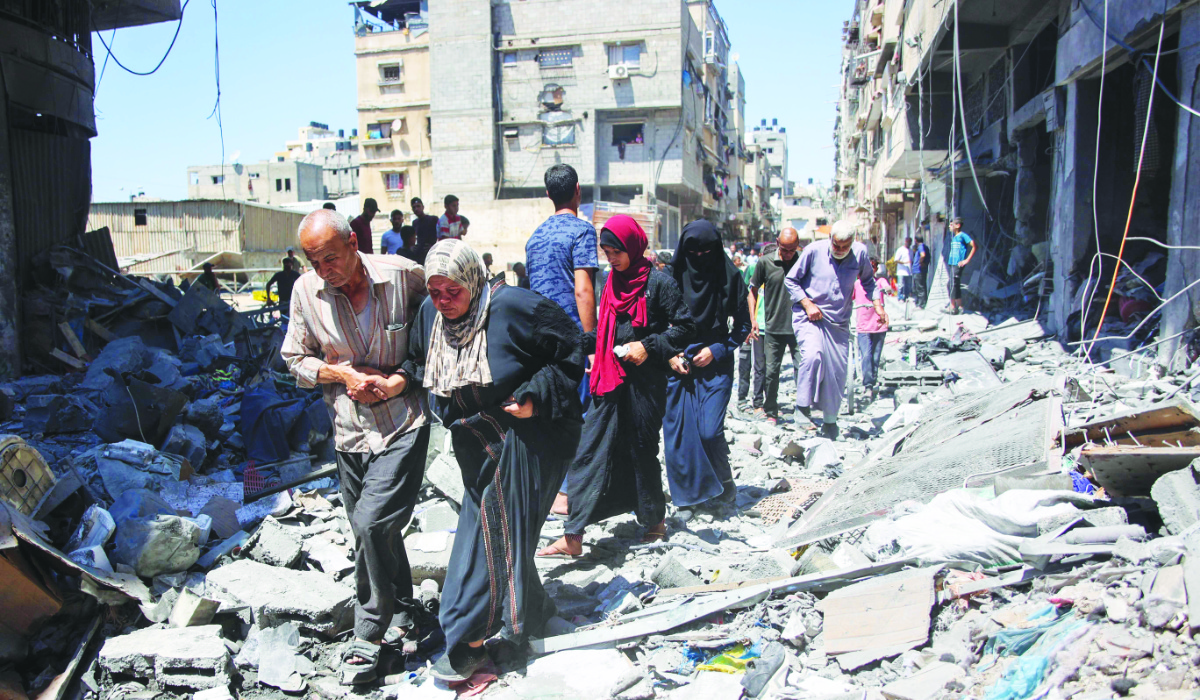 People make their way through the rubble of buildings destroyed during Israeli bombardment at Al-Shati refugee camp in Gaza City on Saturday. (AFP)