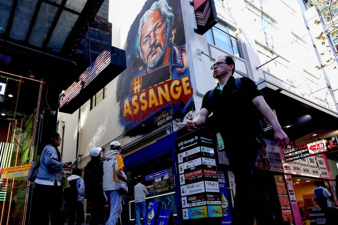 People walk past a mural of Wikileaks founder Julian Assange on George Street in the central business district of Sydney on June 25, 2024. (AFP)