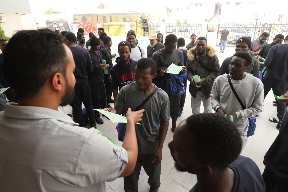 Irregular Nigerian migrants are given documents prior to their departure by coach to Mitiga International Airport from the anti-migration bureau, tasked with coordinating deportations of foreigners who are in the country illegally, in Tripoli on Jun. 25, 2024. (AFP)