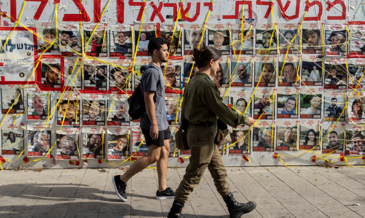 People walk by posters of hostages kidnapped during the deadly October 7 attack on Israel by Hamas, displayed at a plaza now dubbed as "Hostages Square", in Tel Aviv, Israel June 24, 2024. (Reuters)
