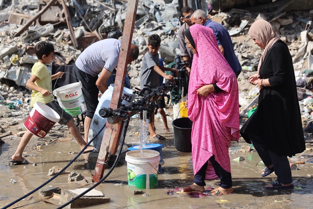Palestinians fill water from a standpipe errected in the Jabalia refugee camp, in the northern Gaza Strip. (AFP)