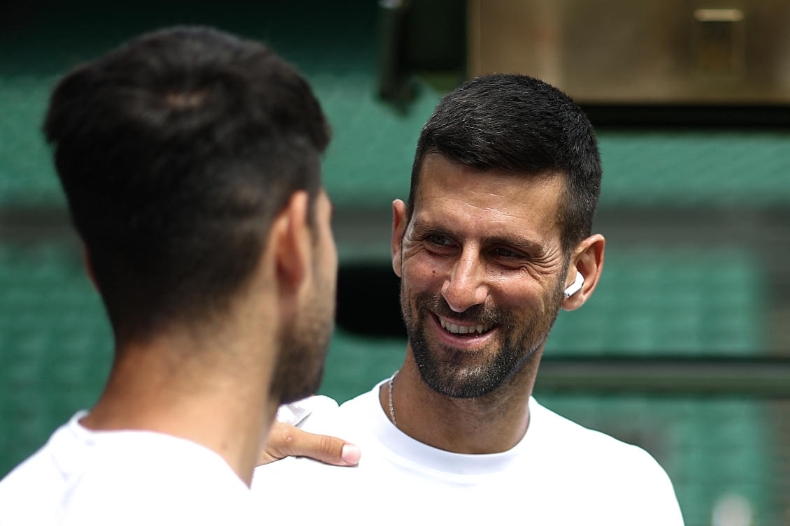 Serbia’s Novak Djokovic smiles at Spain’s Carlos Alcaraz during a warm up session on center court at the All England Lawn Tennis Club, in west London on Jun. 27, 2024, the week before the Wimbledon Championships tennis tournament is due to start on July 1. (AFP)
