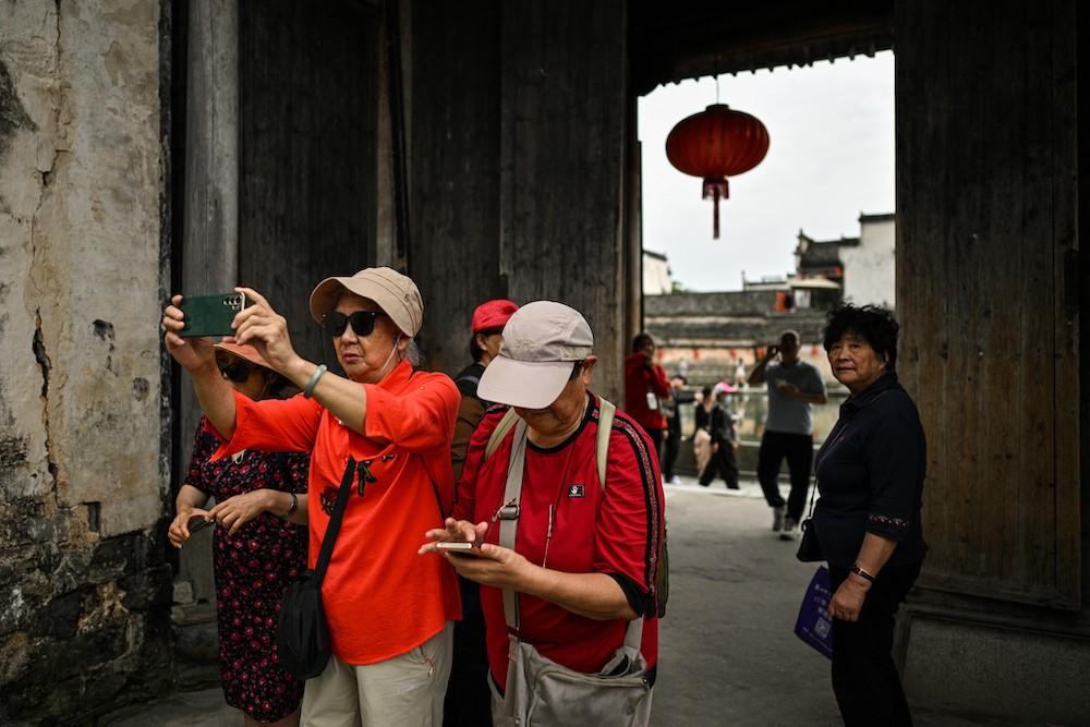 Above, tourists visit the Hongcun Wangshi ancestral temple in Hongcun village, in eastern China’s Anhui province, on May 12, 2024. Beijing has assured Taiwanese ‘compatriots’ they ‘do not need to have the slightest worry when they come to or leave mainland China.’ (AFP)