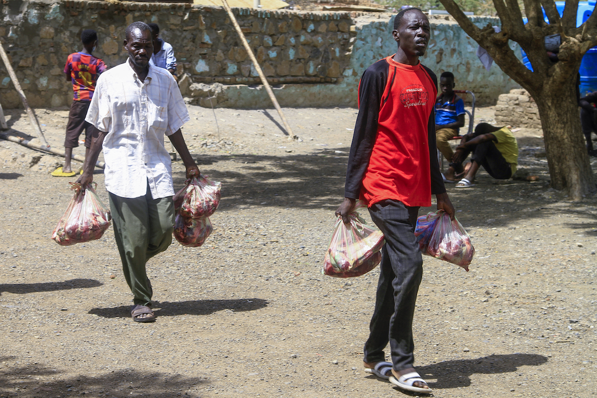 People carry parcels of meat from freshly-slaughtered sacrificial animals in the eastern city of Gedaref. (File/AFP)