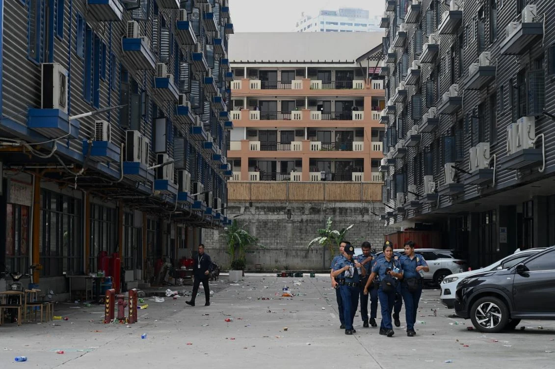 Policemen walk inside a compound, where police raided buildings in Metro Manila on June 27, 2023. (AFP)