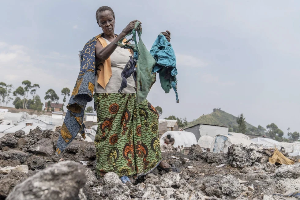 A displaced person living in the Muganga camp with her children and grandchildren near Goma, Democratic Republic of the Congo, gathers belongings on June 6, 2024 after a fire at a displacement camp in the east destroyed around 50 makeshift tents, leaving dozens of families without shelter. (AFP)