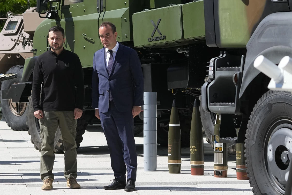 Ukrainian President Volodymyr Zelensky stands with French Defense minister Sebastien Lecornu by military vehicles and a Caesar self-propelled howitzer during a visit at a division of the French Defense ministry on June 7, 2024 in Paris. (AP)