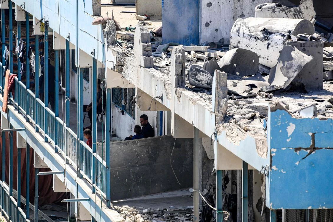 A man and children are pictured in the balcony of a school run by UNRWA that was previously hit by Israeli bombardment, in the Nuseirat camp in the central Gaza Strip on Jun. 7, 2024. (AFP)