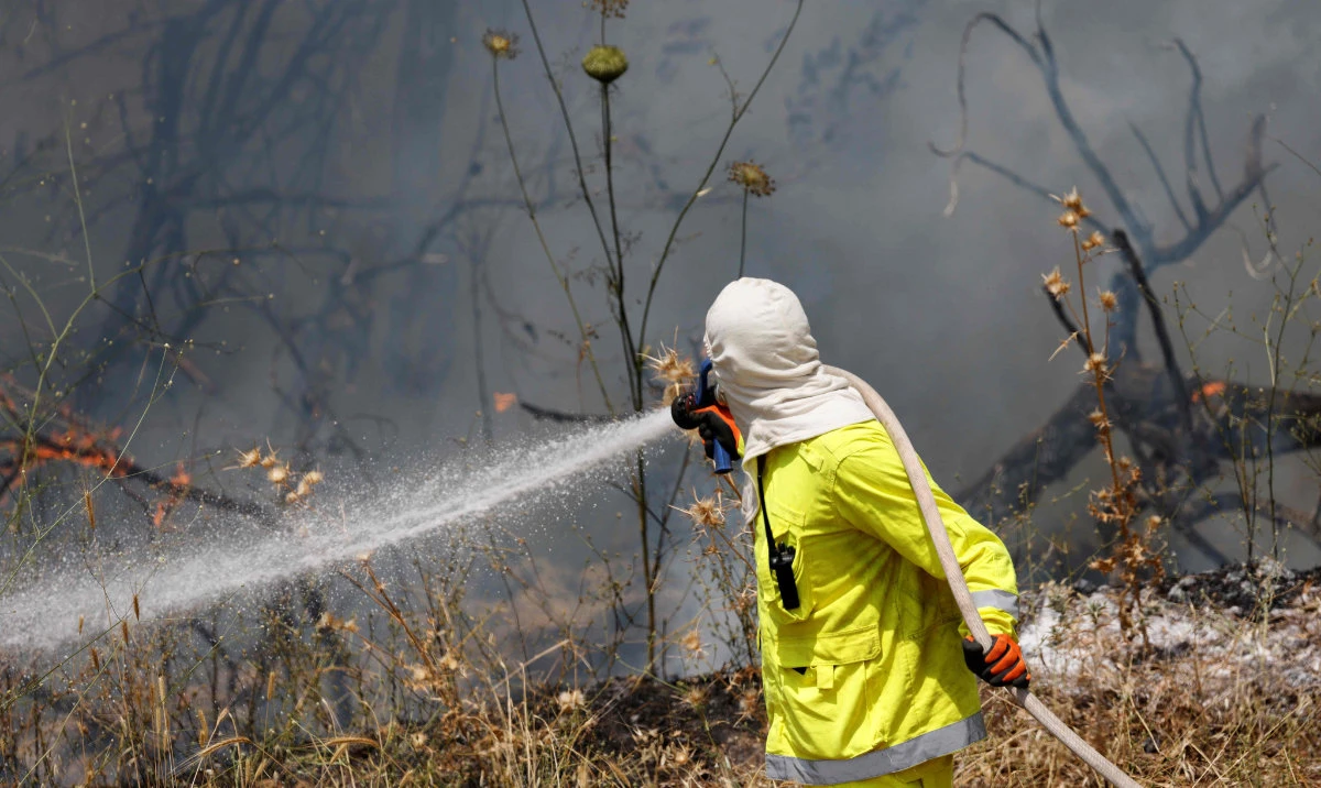 An Israeli firefighter puts out flames in a field after rockets launched from southern Lebanon landed on Banias area in the Israel-annexed Golan Heights on June 9, 2024, amid ongoing cross-border clashes between Israeli troops and Hezbollah fighters. (AFP)