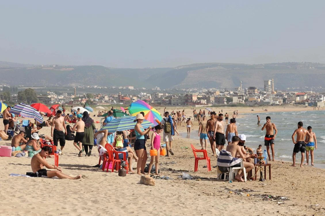 People spend time on the beach in the port city of Tyre in southern Lebanon on June 8, 2024, amid ongoing cross-border tensions with Israel. Lebanon's Hezbollah, a Hamas ally, and Israel have been trading near-daily fire since the Gaza war was trigged by the Palestinian militant group's October 7 attack on southern Israel. Lebanese beachgoers, many from the country's south, where Hezbollah largely holds sway, try to disconnect from news of war at the beach in Tyre. (Photo by ANWAR AMRO / AFP)