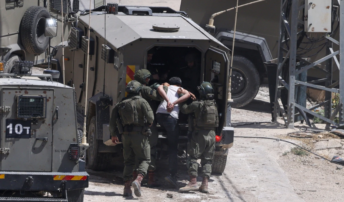 Israeli soldiers detain a Palestinian man during a raid in the occupied West Bank town of Deir Al-Ghusun near Tulkarem on May 4, 2024. (AFP/File)