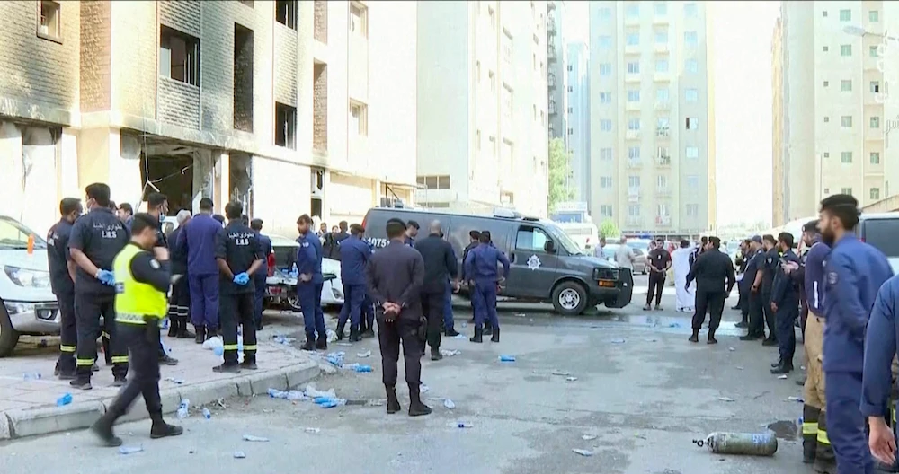 Rescuers arrive at the site of a building that caught fire in Kuwait, Wednesday, June 12, 2024. (Kuwait TV via AP)