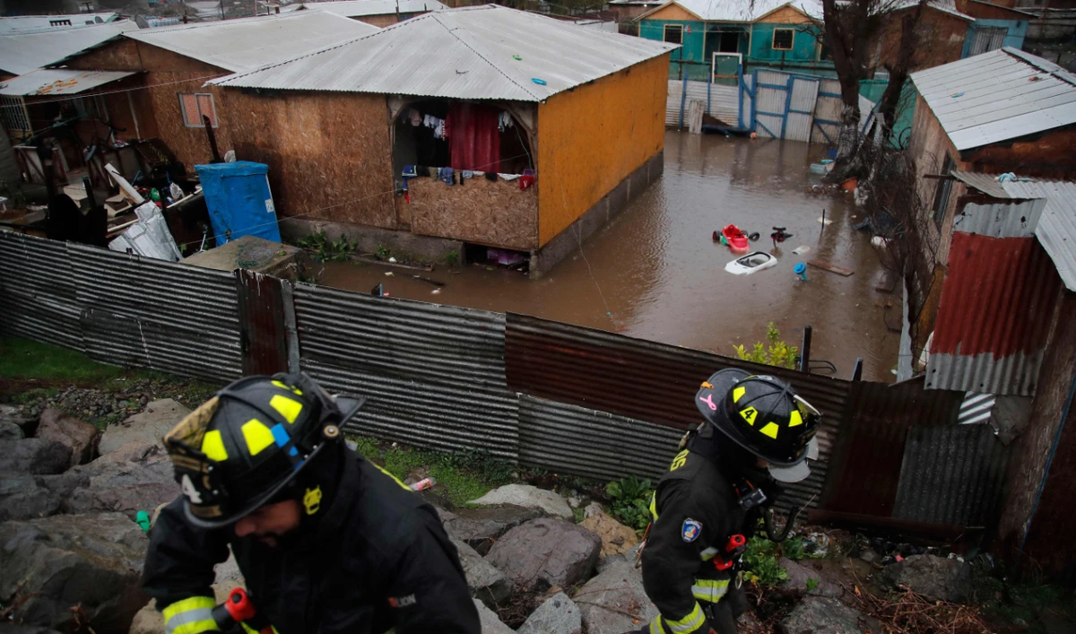 Firefighters evacuate residents of a shantytown located on the banks of the Mapocho River, as the river would overflow due to heavy rains in the commune of Talagante, Santiago, on June 13, 2024. (AFP)