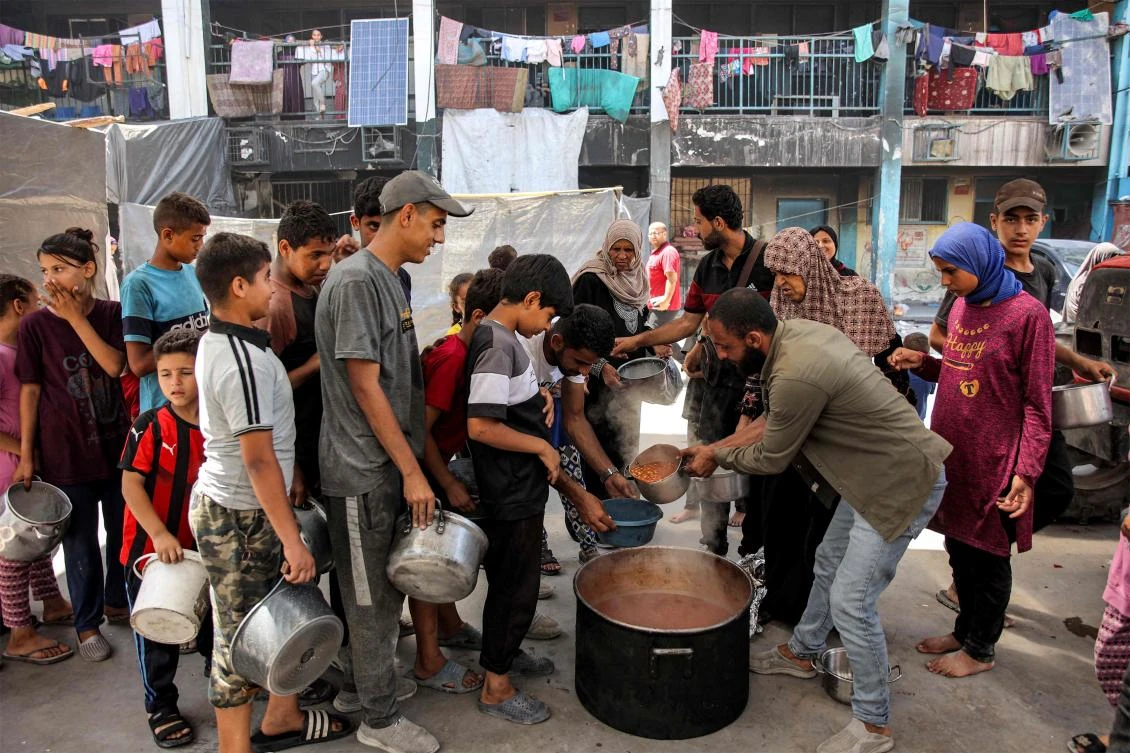 Children queue with pots to receive food aid from a kitchen at the Abu Zeitun school run by UNRWA in the Jabalia camp for Palestinian refugees in the northern Gaza Strip on June 13, 2024. (AFP)