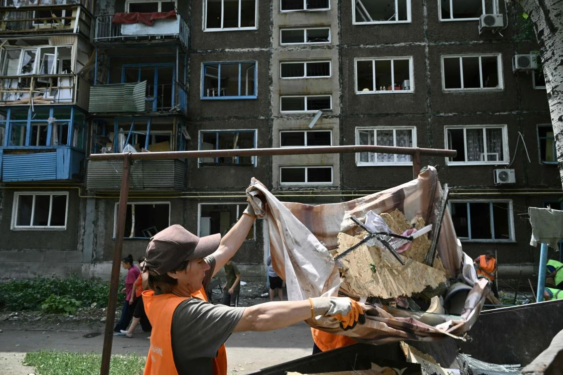 Communal workers clear debris next to a damaged residential building following overnight Russian strike in the town of Selydove, Donetsk region on June 14, 2024. (AFP)