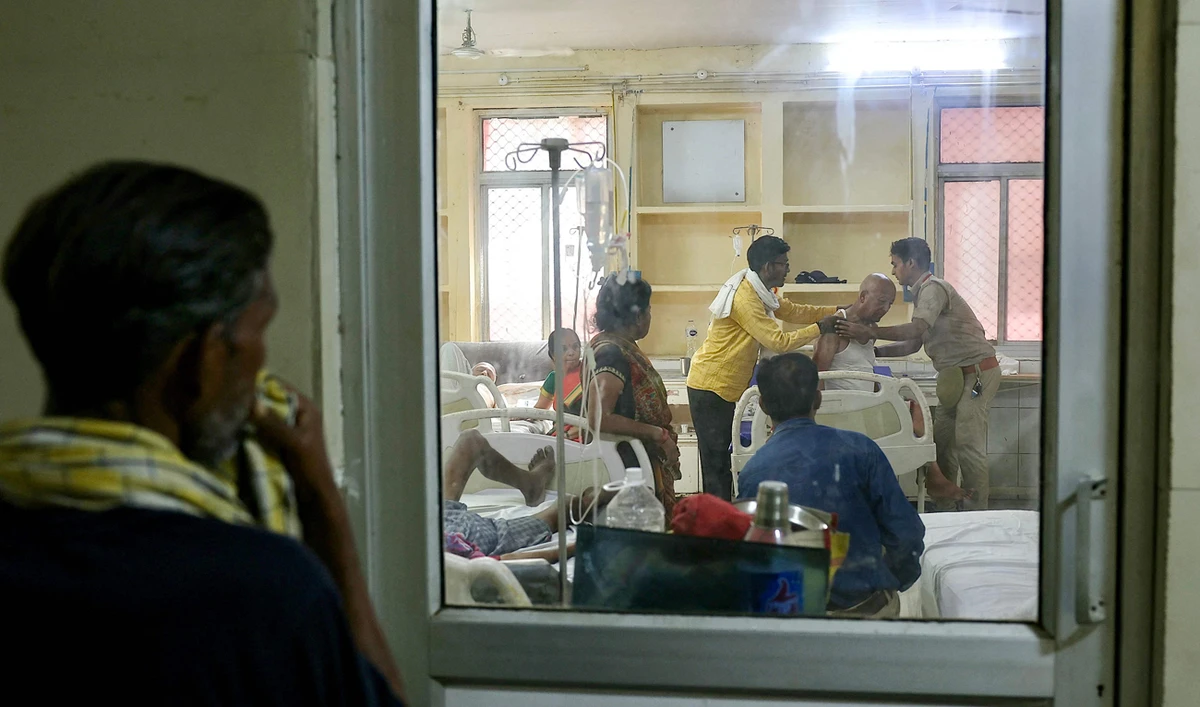 People watch as a patient suffering from heat stroke is helped to get up inside an emergency room in a government hospital during a severe heatwave in Varanasi on May 30, 2024. (AFP)