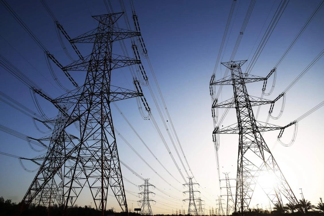 The sun sets behind overhead power lines as the Kuwaiti Ministry of Electricity requested citizens to ration their electricity usage at peak times due to outages caused by the increased pressure on power stations amid soaring temperatures and heightened energy demand.(AFP)