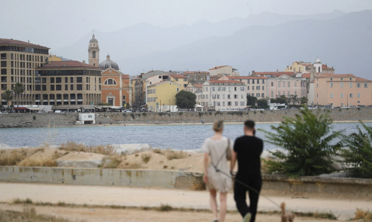 A couple walk along the seafront in Ajaccio, on the French Mediterranean island of Corsica, on June 20, 2024, after an alert of atmospheric pollution was activated due to Sahara particules in the air. (AFP)