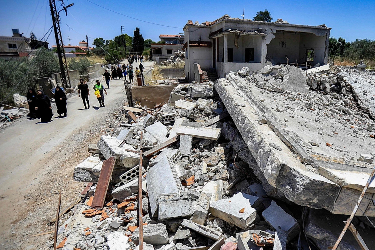 People walk past the rubble of a building that was destroyed by previous Israeli bombardment in the village of Yaroun in south Lebanon near the border with Israel on June 21, 2024. (AFP)
