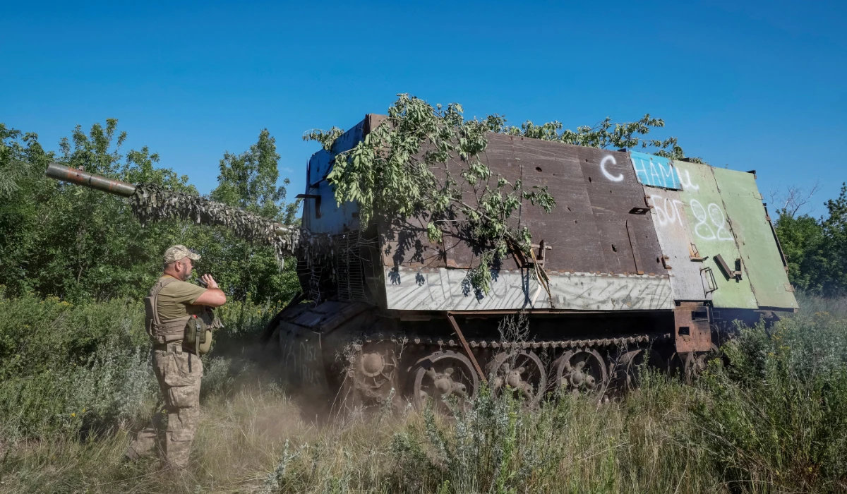 A Ukrainian serviceman of the 22nd Separate Mechanised Brigade stands next to a Russian T-62 Soviet main battle tank crafted with anti-drone protection that was recently captured by his unit, amid Russia's attack on Ukraine, at an undisclosed location in Donetsk region, Ukraine, June 19, 2024. (REUTERS)