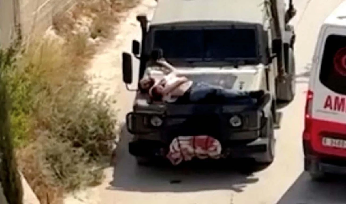 Israeli army straps Palestinian on military jeep during raid in Jenin, in this screengrab from a video, in the Israeli-occupied West Bank, June 22, 2024. (Reuters)
