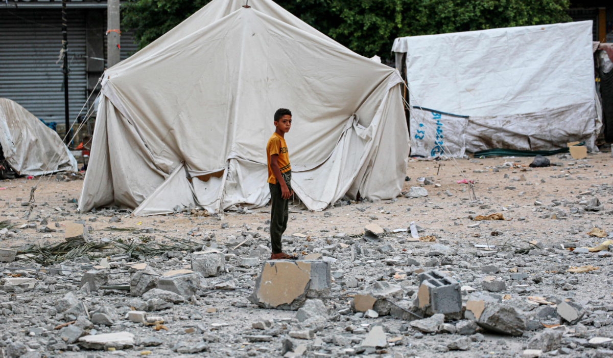 A Palestinian youth stands on rubble close to tents housing internally displaced people, erected in the square near the Deir al-Balah municipality building, destroyed following Israeli bombardment of Deir al-Balah, in the central Gaza Strip on June 28, 2024, amid the ongoing conflict between Israel and the Palestinian Hamas militant group. (AFP)