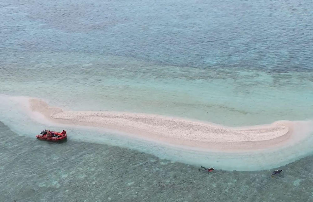 Above, a frame grab from a video released on June 7, 2024 shows Philippine Coast Guard divers and marine scientists surveying part of Sabina shoal in the waters of South China Sea. (Philippine Coast Guard/AFP)