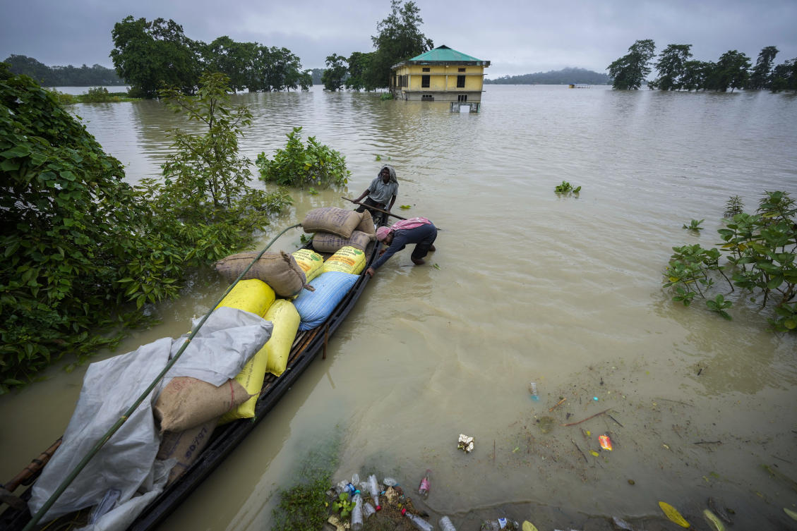 Flood affected people travel transport sacks of rice in a country boat in Mayong village in Morigaon district in the northeastern state of Assam, India, Tuesday, July 2, 2024. (AP)