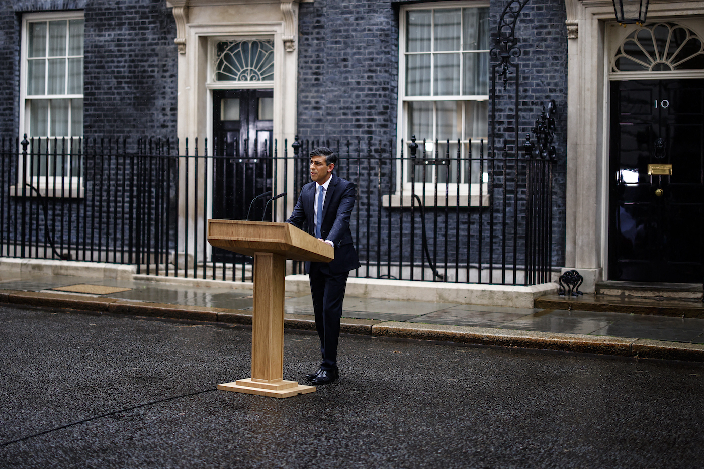 Britain’s Prime Minister Rishi Sunak, soaked in rain, stands at a lecturn as he delivers a speech to announce July 4 as the date of the UK’s general election. (File/AFP)