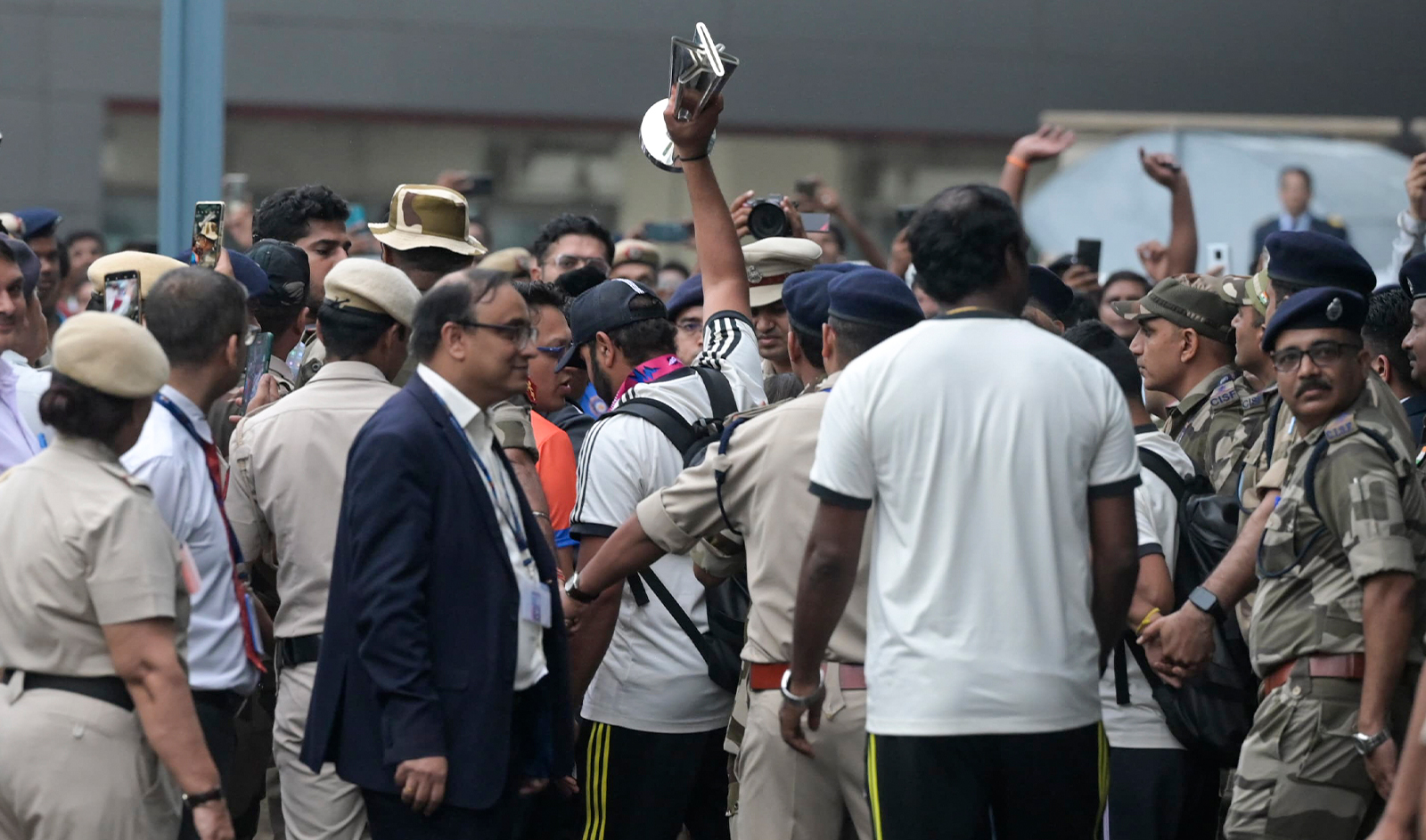 India's captain Rohit Sharma is surrounded by officials as he lifts the winners' trophy after arriving at the Indira Gandhi International Airport in New Delhi, India, on July 4, 2024. (AP)