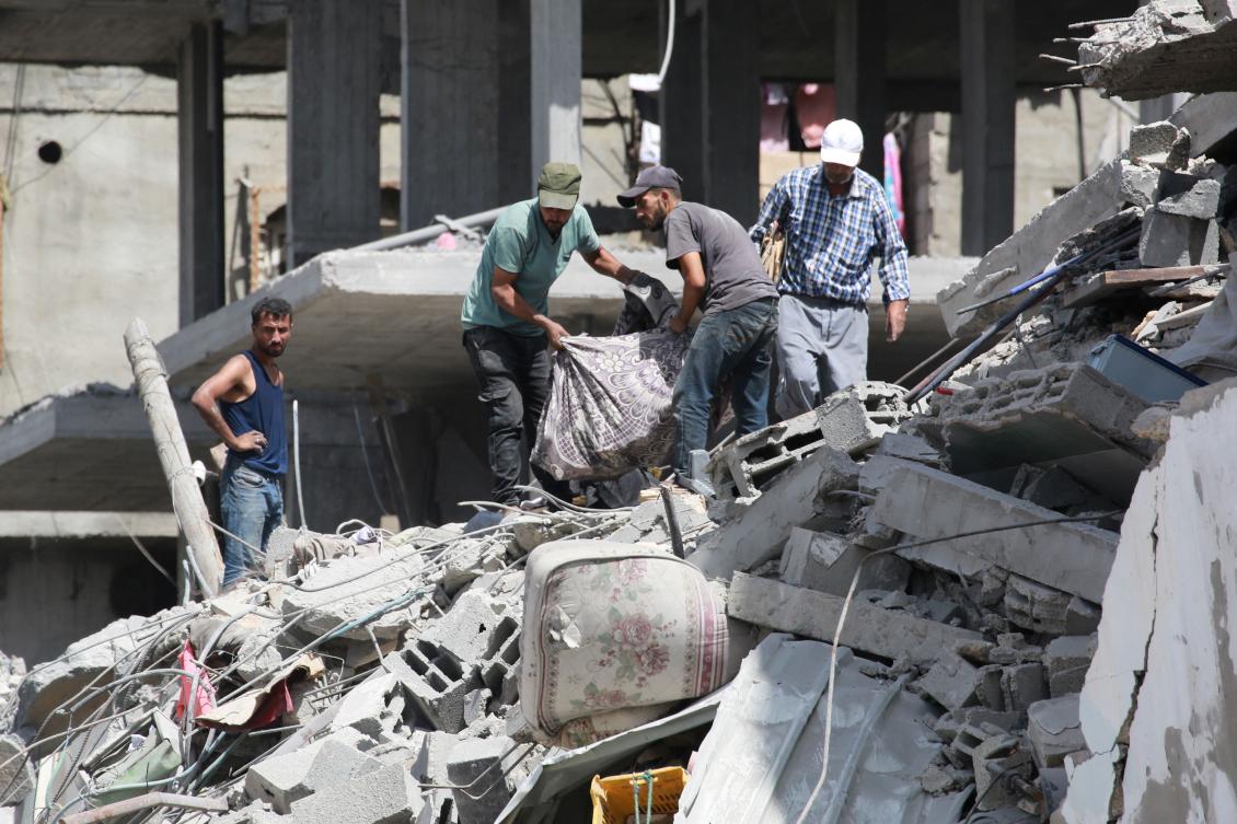 Palestinians recover belongings from the rubble after an Israel strike the previous day on a five-story building next to a school sheltering displaced people, in Khan Yunis in the southern Gaza Strip on Jul. 4, 2024. (AFP)