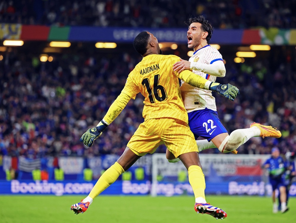France's Theo Hernandez, right, celebrates with goalkeeper Mike Maignan after scoring the winning goal in shootout to defeat Portugal in a quarterfinal match at the Euro 2024. (dpa via AP)