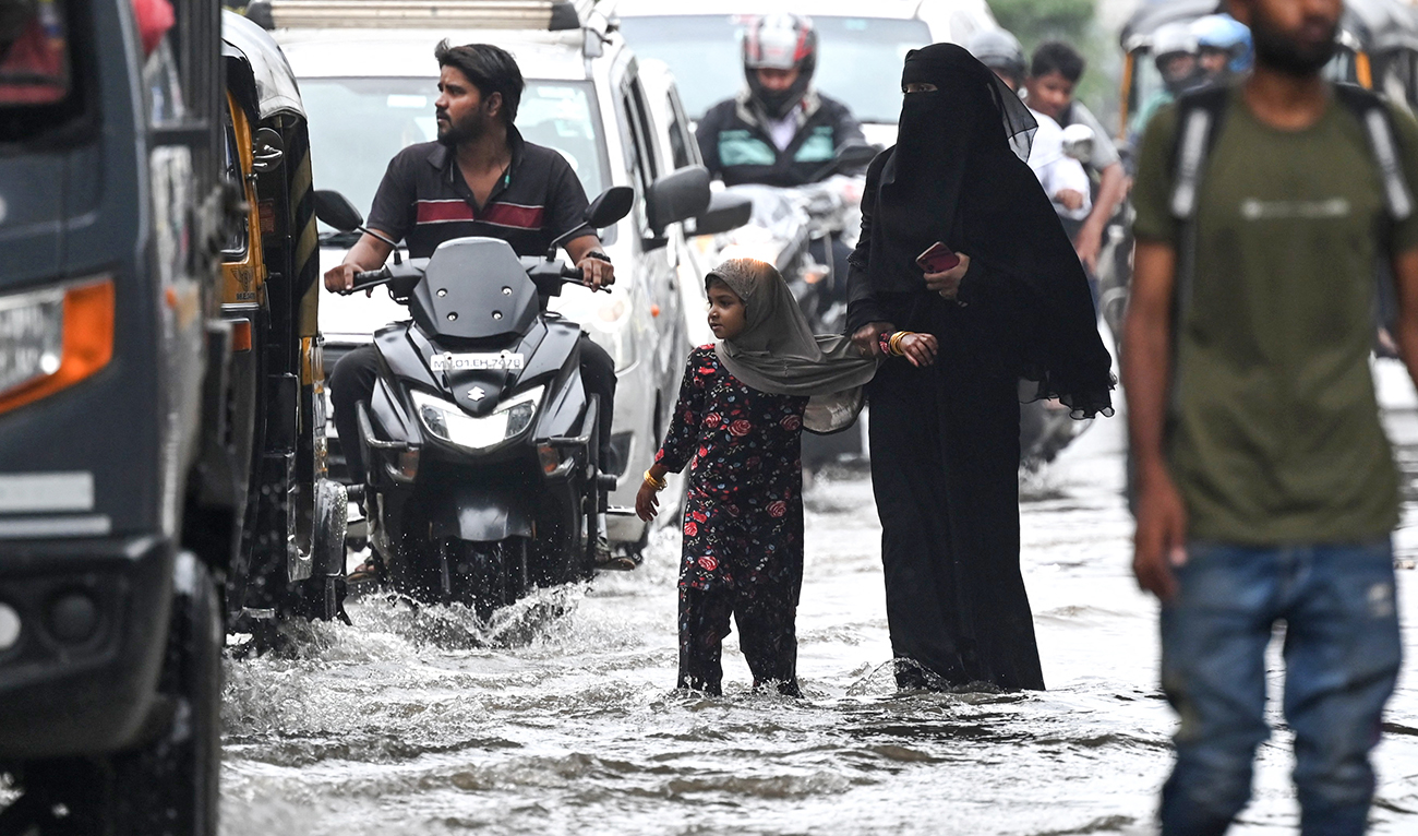 Pedestrians walk through a flooded street after rain showers in Mumbai on July 8, 2024. (AFP)