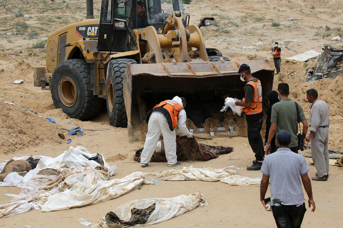 Health workers recover bodies carried by a bulldozer after they were unearthed from a mass grave found in the Nasser Medical Complex in the southern Gaza Strip. (File/AFP)