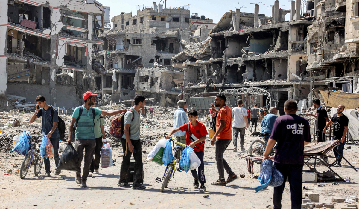 People walk past rubble and damaged buildings in the Tuffah district east of Gaza City on July 8, 2024 amid the ongoing conflict in the Palestinian territory between Israel and Hamas. (AFP)