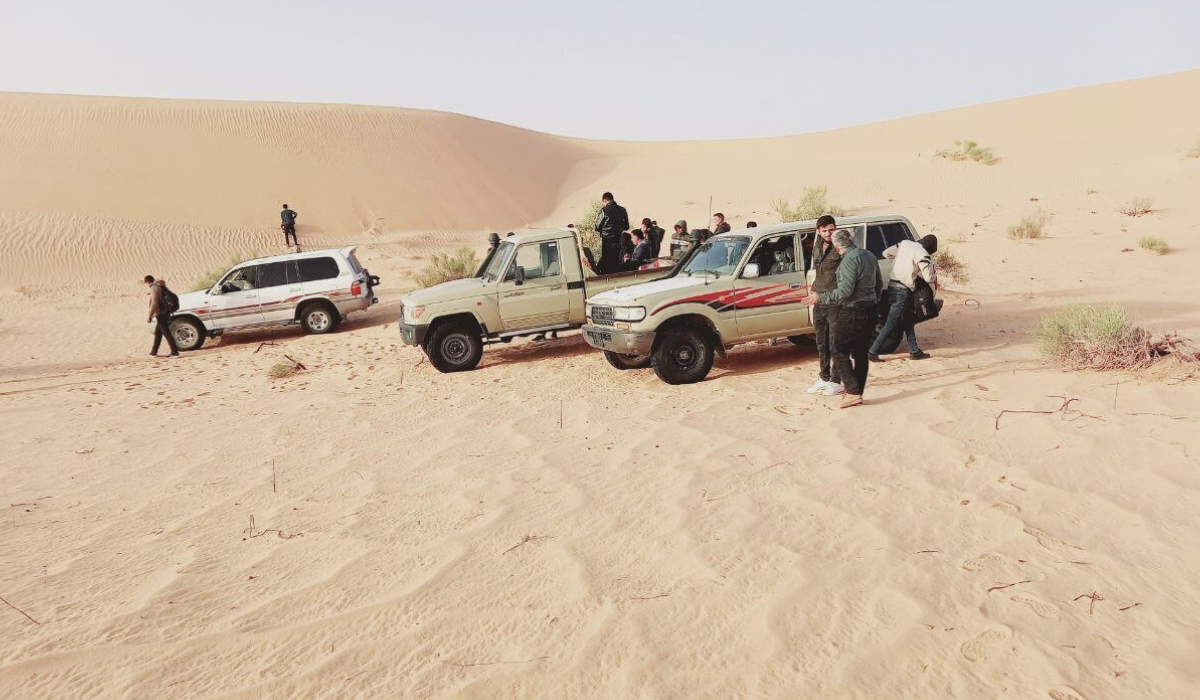 In this UGC photo Syrian Kurdish migrants wait for cars to arrive at a meeting point in a desert near the Libyan-Algeria border in the town of Debdeb, Algeria, on Monday, March 28, 2022. (AP file photo)