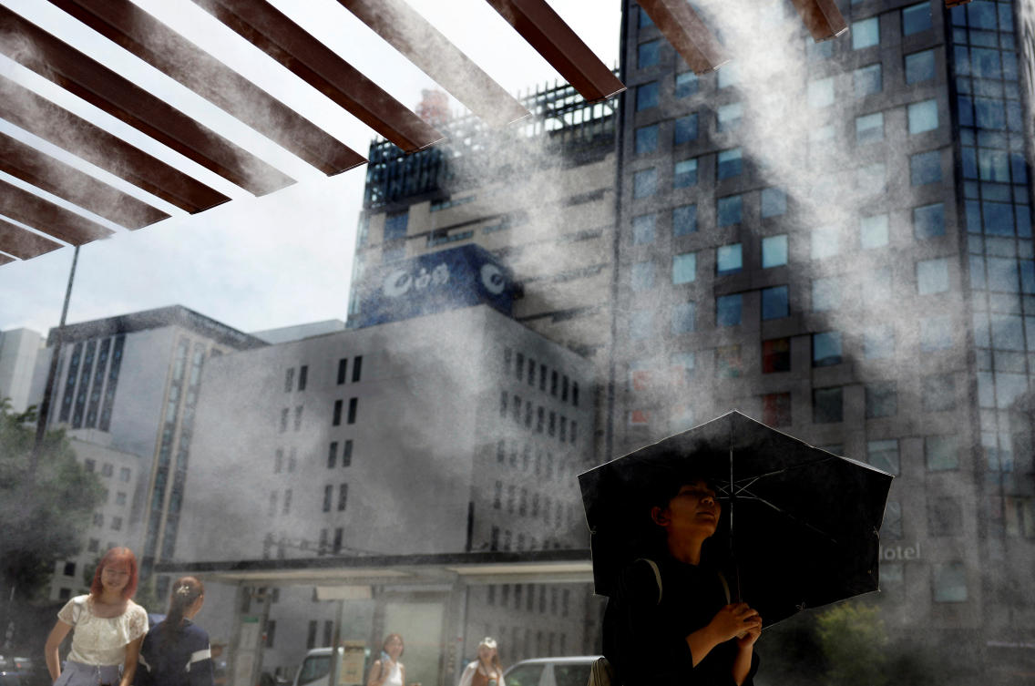 Passersby take a break under a cooling mist as the Japanese government issued a heatstroke alert in Tokyo and other prefectures, in Tokyo, Japan July 9, 2024. (Reuters)