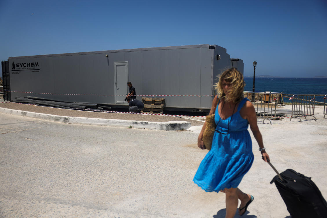 A tourist walks past a desalination plant, on the island of Naxos, Greece, June 20, 2024. (Reuters)