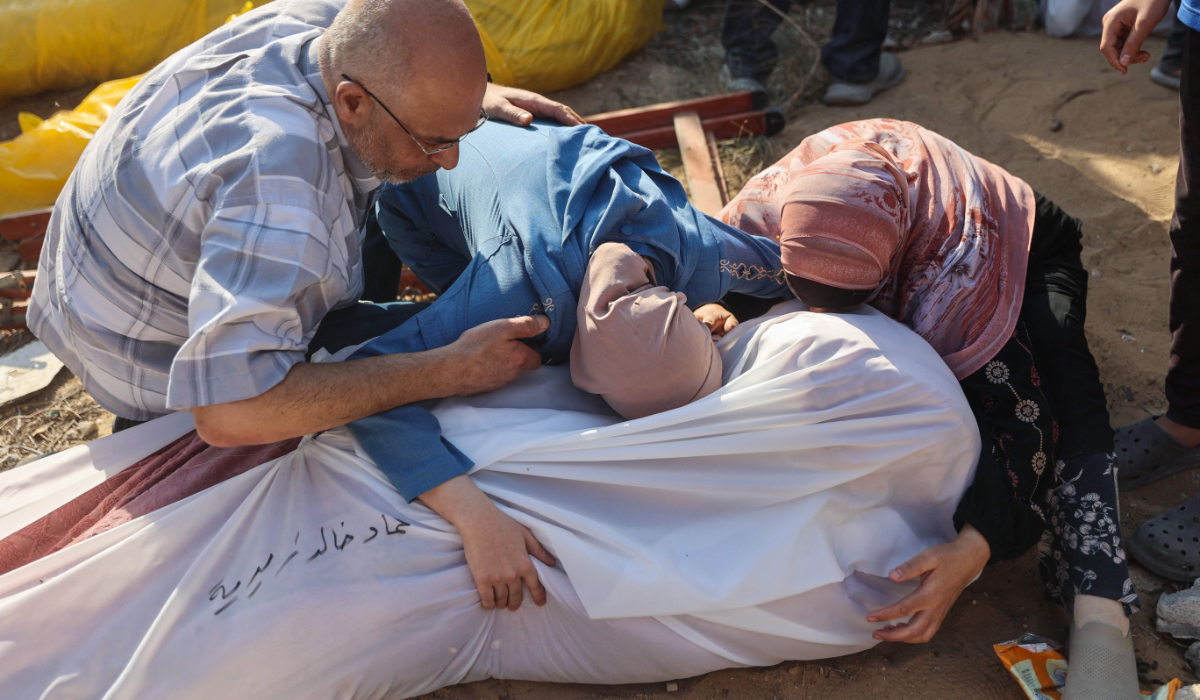 People mourn by relatives bodies, found under rubble or on the street, ahead of their burial in western Gaza City's Al-Sinaa neighbouhood on July 12, 2024, following the withdrawal of Israeli troops from the area amid the ongoing conflict between Israel and the militant Hamas group in the besieged Palestinian territory. (AFP)