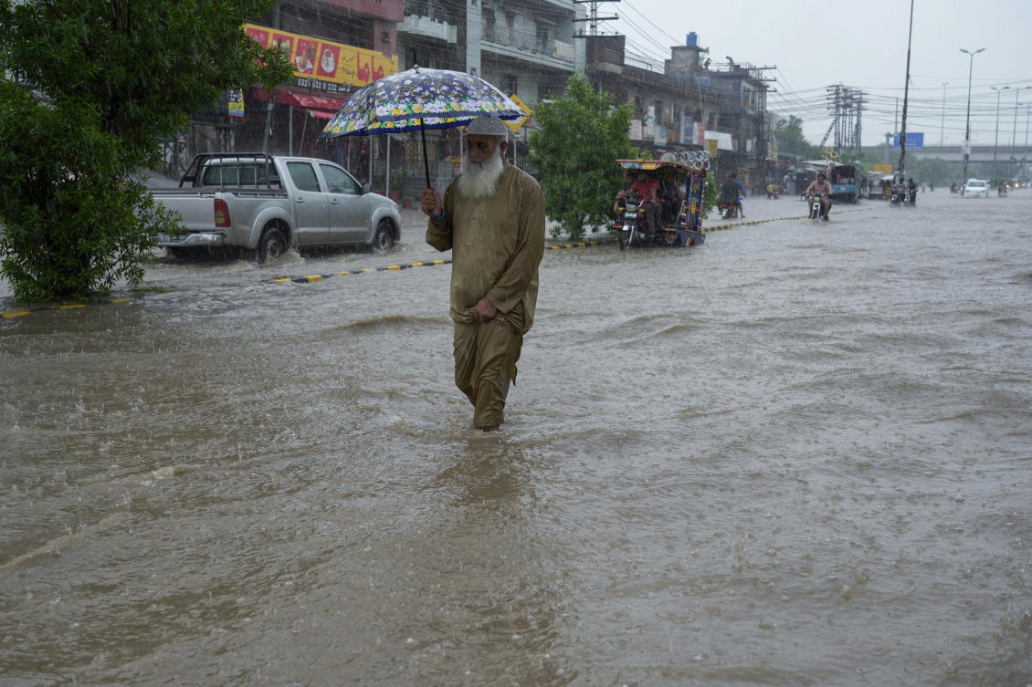 A man holds an umbrella and wades through a flood road during heavy rainfall in Lahore, Pakistan, Friday, July 12, 2024. (AP Photo/K.M. Chaudary)