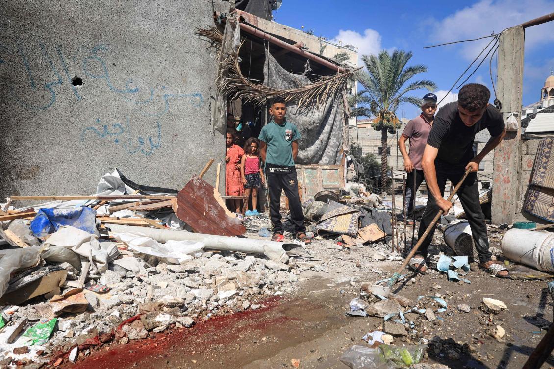 A Palestinian man clears rubble and blood in front of a house hit by Israeli bombing in Deir el-Balah in the central Gaza Strip on July 13, 2024. (AFP)