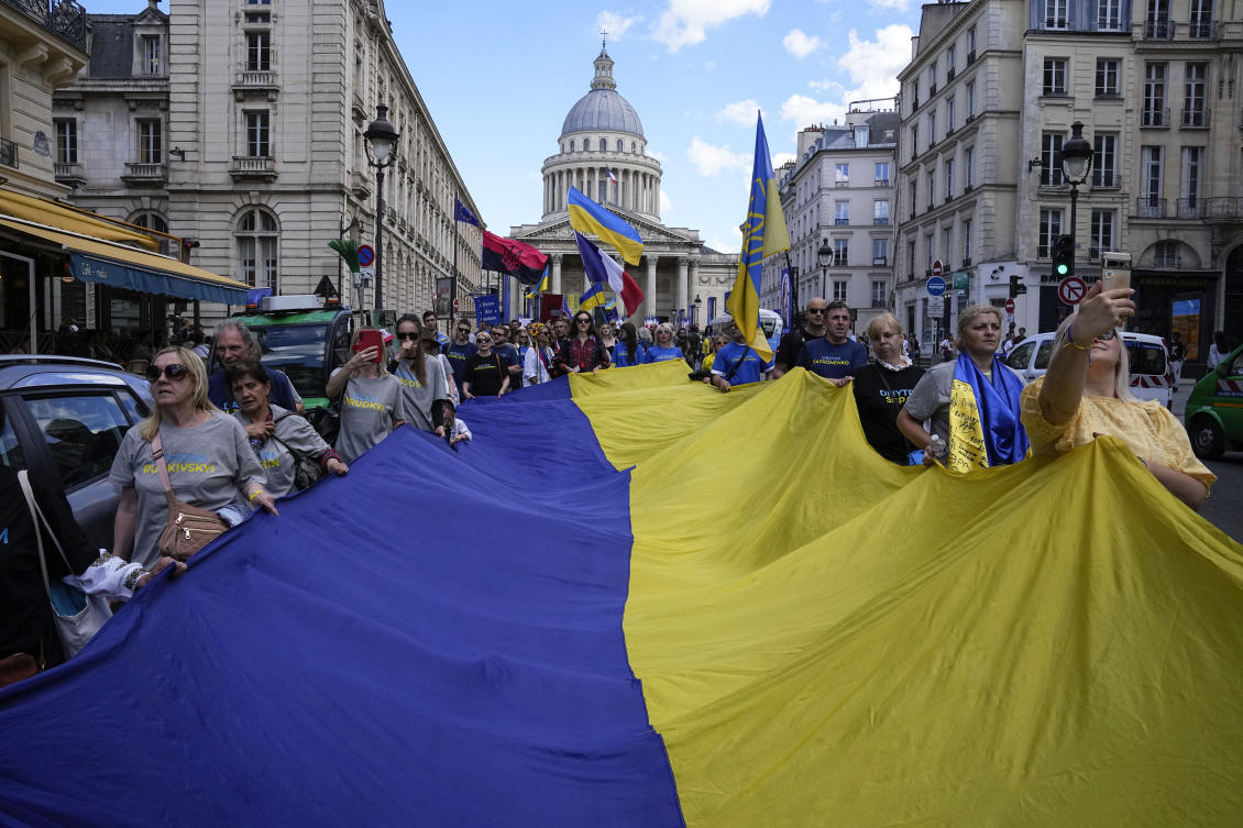 Members of the Union of Ukrainians of France hold a giant Ukrainian flag as they march to honor the hundreds of Ukrainian athletes who have perished since the Russian invasion of their homeland on Jul. 13, 2024 in Paris. (AP)